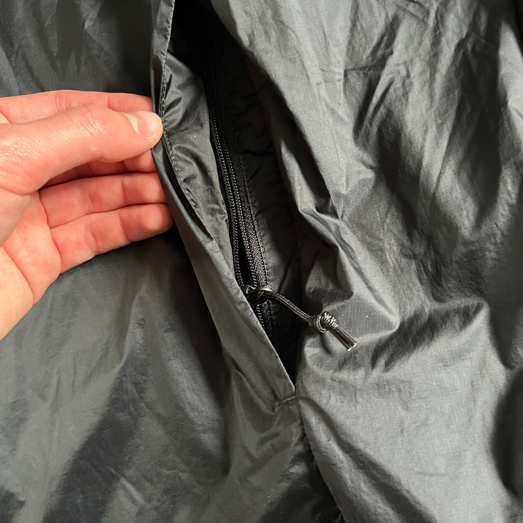 Nike ACG “Cinder Cone” Windbreaker in black, crafted from 100% recycled nylon ripstop. Features a lightweight, water-repellent shell, half-zip closure, and extended collar for added coverage. Designed with no shoulder seams for mobility and finished with printed ACG chest branding, two zippered pockets, and an internal baby carabiner.