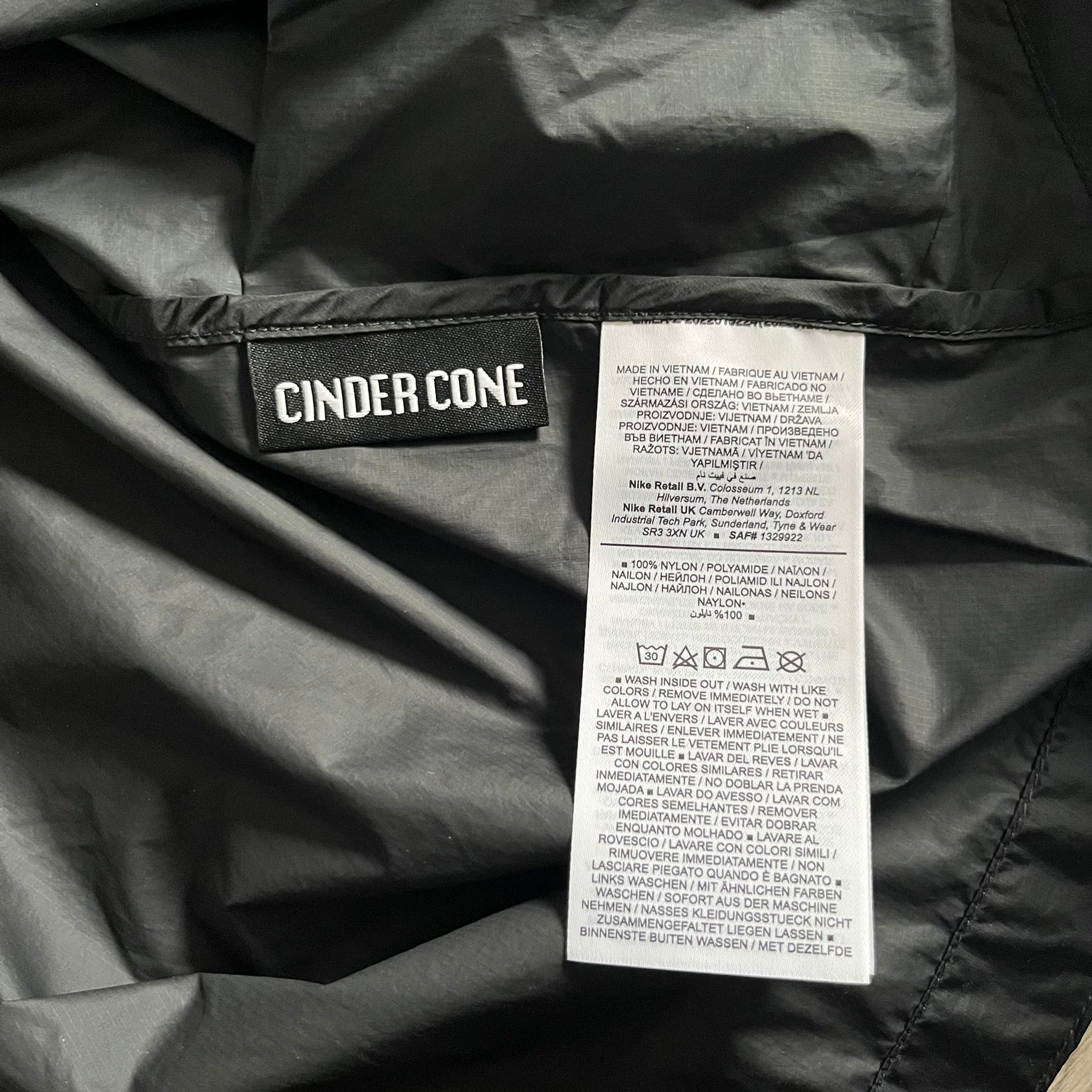 Nike ACG “Cinder Cone” Windbreaker in black, crafted from 100% recycled nylon ripstop. Features a lightweight, water-repellent shell, half-zip closure, and extended collar for added coverage. Designed with no shoulder seams for mobility and finished with printed ACG chest branding, two zippered pockets, and an internal baby carabiner.