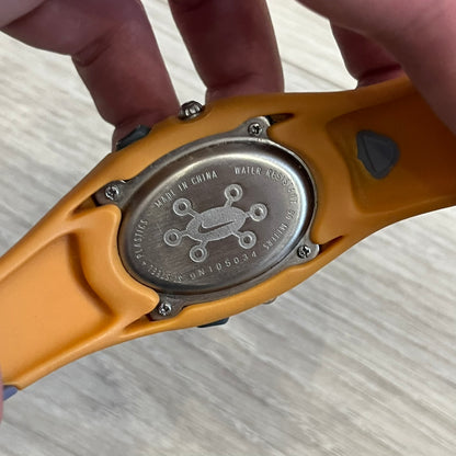 Nike ACG Thermal Gauge Watch featuring an ani-digi display with temperature, date, timer, alarm, and counter functions. Designed with a durable stainless-steel and plastic build, a white dial with grey outline, and an orange strap with the ACG logo. Water-resistant up to 50m, this Nike ACG outdoor watch blends utility with signature 90s–2000s adventure styling.