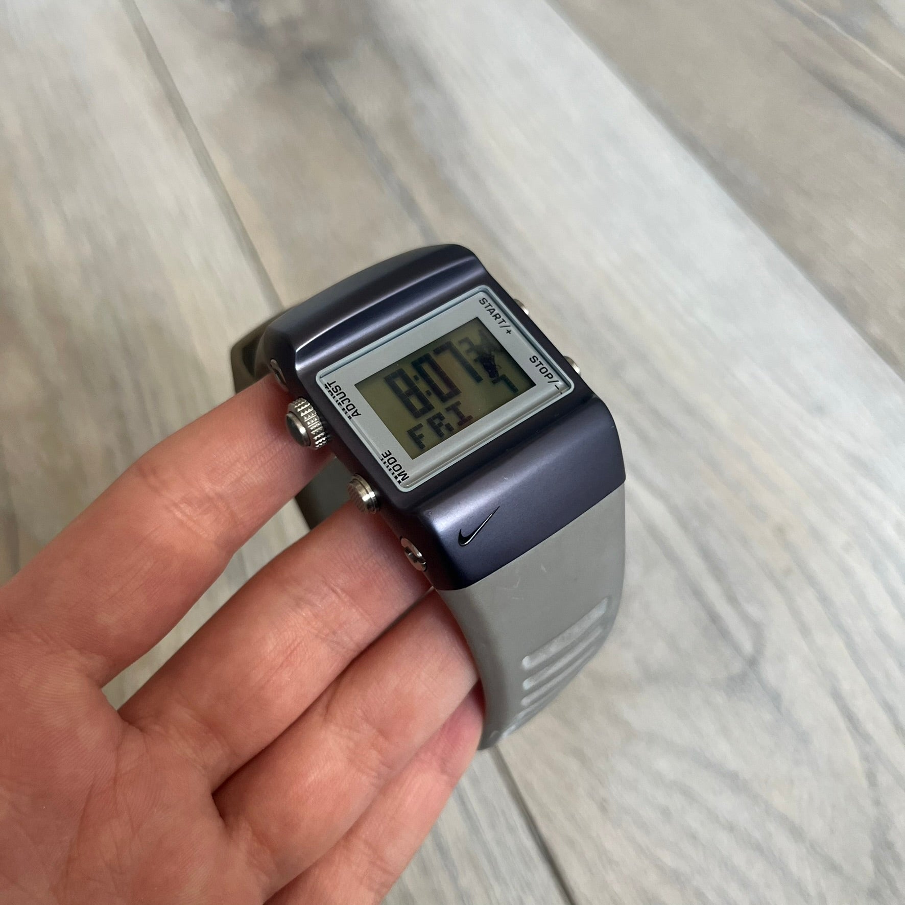 Nike Anvil Comold Reg Digital Watch WC0038 is a digital wristwatch featuring a dark purple/violet aluminum and stainless steel case with a white-outlined display. The watch includes four side buttons, a digital screen, and grey rubber straps, constructed from a mix of aluminum, stainless steel, and plastic. It is water resistant up to 100 meters, powered by fresh batteries, and comes with the original box.