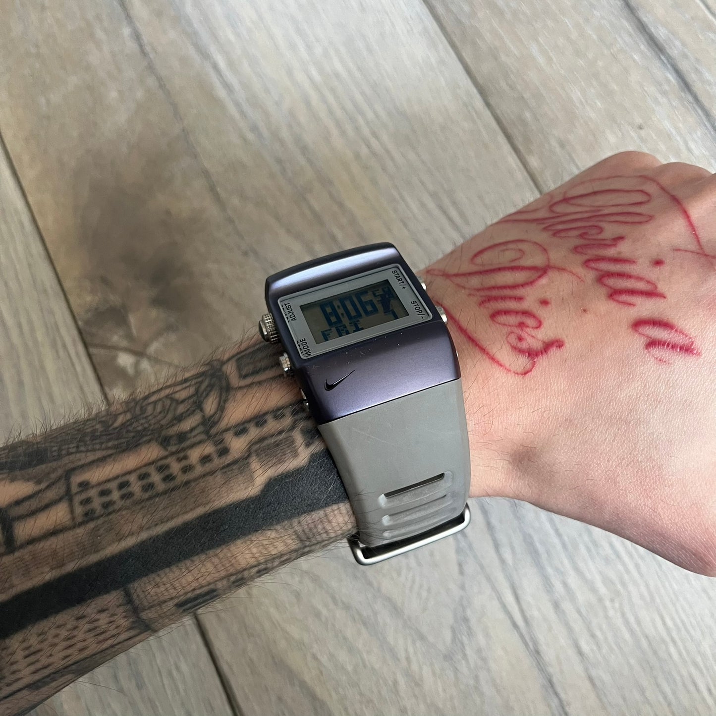 Nike Anvil Comold Reg Digital Watch WC0038 is a digital wristwatch featuring a dark purple/violet aluminum and stainless steel case with a white-outlined display. The watch includes four side buttons, a digital screen, and grey rubber straps, constructed from a mix of aluminum, stainless steel, and plastic. It is water resistant up to 100 meters, powered by fresh batteries, and comes with the original box.