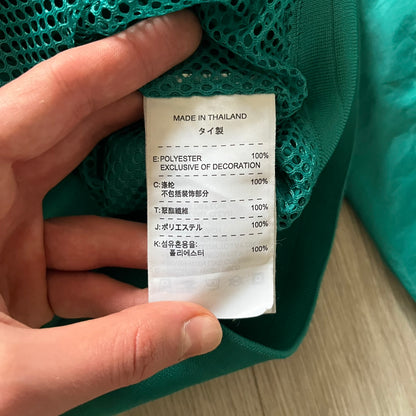 Nike 2008 Australia Olympics Split Windbreaker in teal, detailed with yellow star embroidery inspired by Australia’s national emblem. Designed with double side zippers that let the jacket separate for modular wear. Includes embroidered white Nike logo on the chest and Australian flag details inside both pockets.