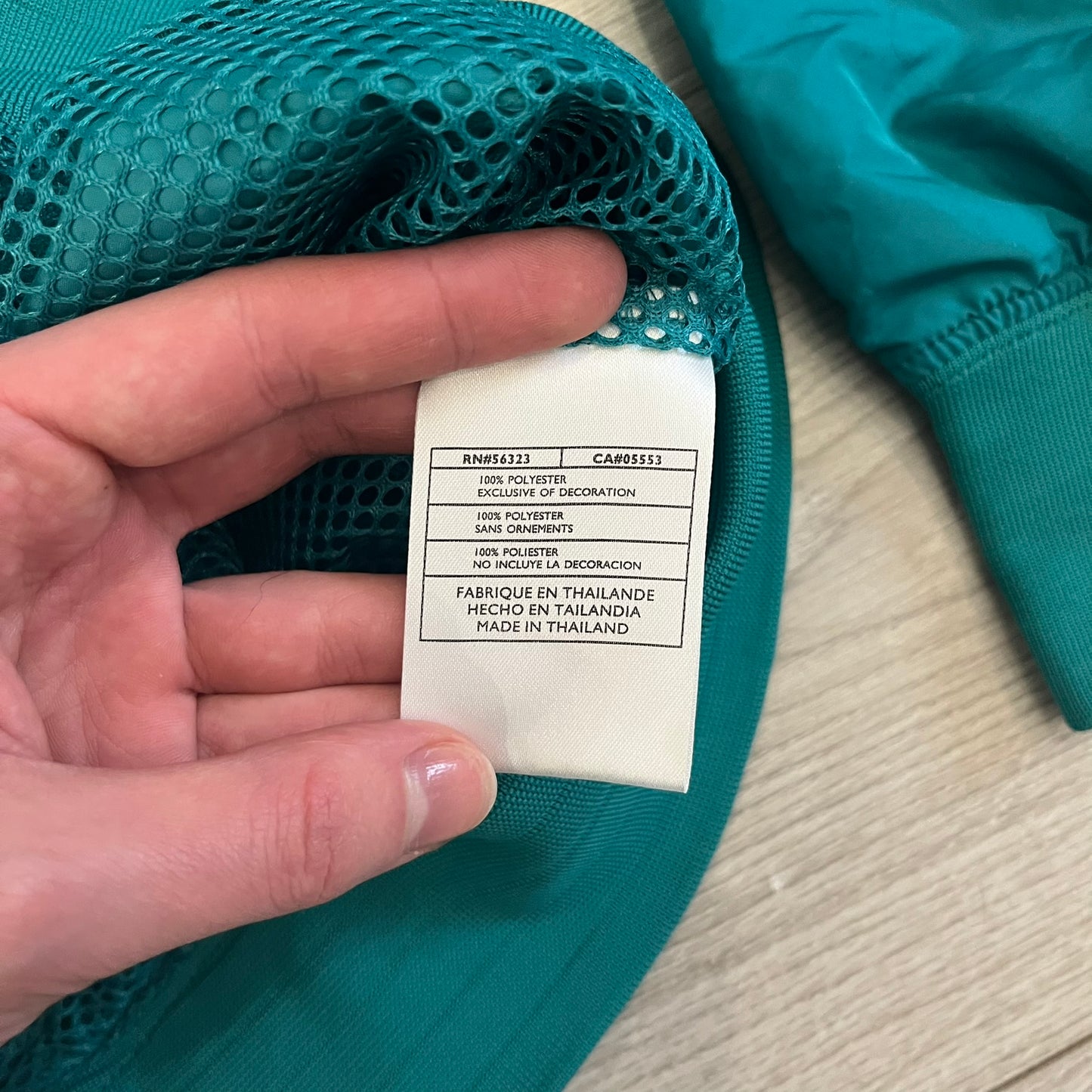 Nike 2008 Australia Olympics Split Windbreaker in teal, detailed with yellow star embroidery inspired by Australia’s national emblem. Designed with double side zippers that let the jacket separate for modular wear. Includes embroidered white Nike logo on the chest and Australian flag details inside both pockets.