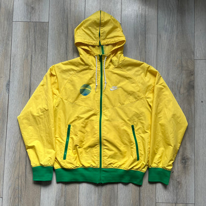 Nike Brazil Olympics Split Windbreaker from 2008, created by designer Jarrett Reynolds. Crafted in yellow with green hems and zippers. Blue circle and white Nike embroidered logo on the chest. This innovative jacket can be zipped apart on both sides and merged with other compatible models. Hidden inside, a small Brazil flags accent completes the concept.