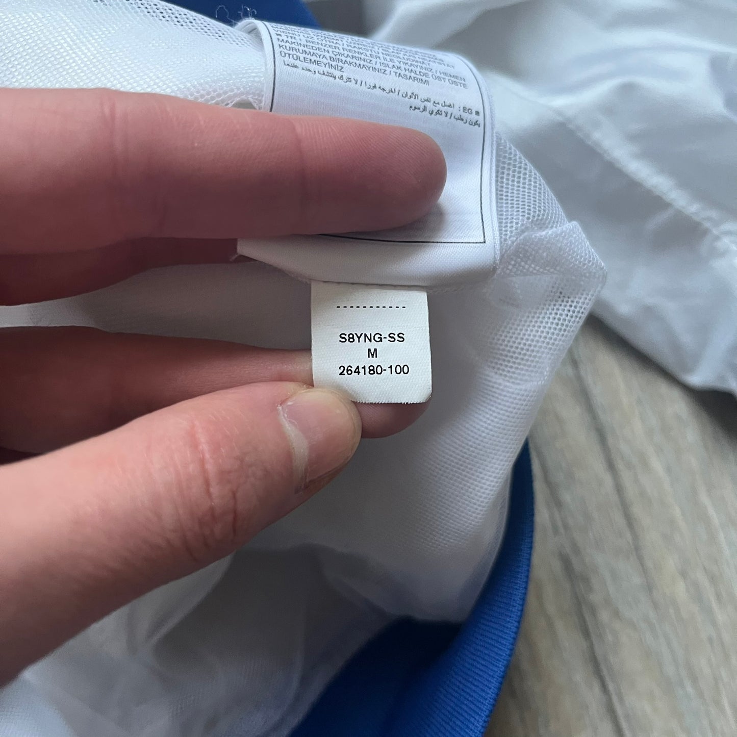 Nike Brazil windbreaker released in 2008 to mark the 50th anniversary of Brazil’s football legacy. Features a split color-block design with white lower panels and sleeves, yellow and green upper section, blue cuffs and hems, and a green hood. Detailed with a gold embroidered Nike logo on the chest, a gold-tone metal Brazil crest pin on the opposite side, and “1958-2008” with a “50” printed on the hood. The hood interior is white with an all-over green star pattern.