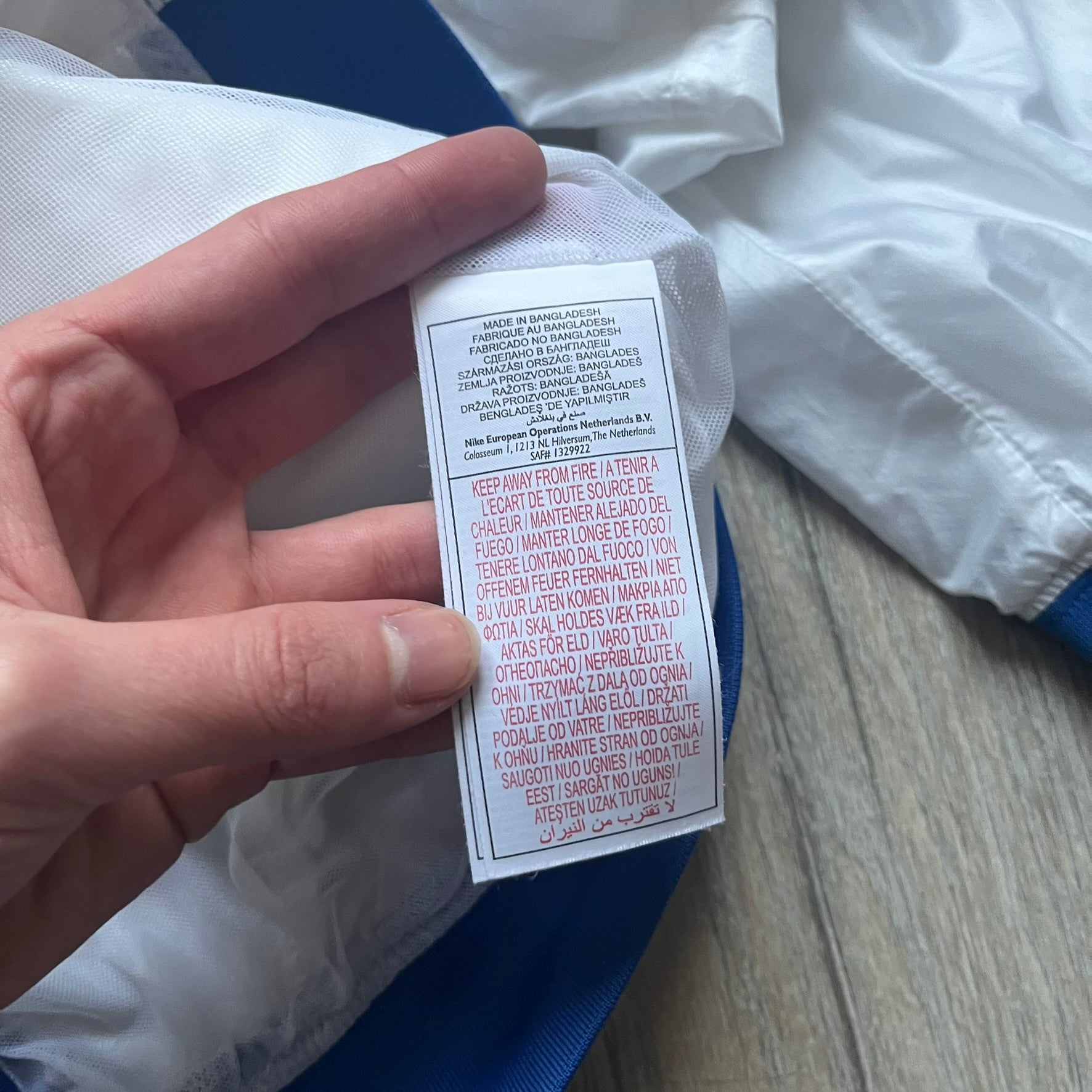 Nike Brazil windbreaker released in 2008 to mark the 50th anniversary of Brazil’s football legacy. Features a split color-block design with white lower panels and sleeves, yellow and green upper section, blue cuffs and hems, and a green hood. Detailed with a gold embroidered Nike logo on the chest, a gold-tone metal Brazil crest pin on the opposite side, and “1958-2008” with a “50” printed on the hood. The hood interior is white with an all-over green star pattern.