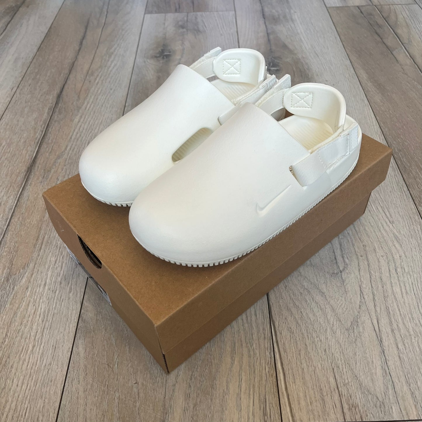 Nike Calm Mule Wmns White Sandals FB2185-100 are women’s slip-on mules finished in a Sail/White colorway, constructed from a single-piece foam upper for a seamless design. The model features water-resistant, easy-to-clean foam with a textured footbed and full-length rubber outsole for traction on wet surfaces. An adjustable and removable heel strap allows for a customizable fit, while side openings provide ventilation.