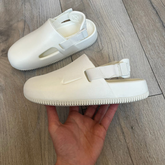 Nike Calm Mule Wmns White Sandals FB2185-100 are women’s slip-on mules finished in a Sail/White colorway, constructed from a single-piece foam upper for a seamless design. The model features water-resistant, easy-to-clean foam with a textured footbed and full-length rubber outsole for traction on wet surfaces. An adjustable and removable heel strap allows for a customizable fit, while side openings provide ventilation.