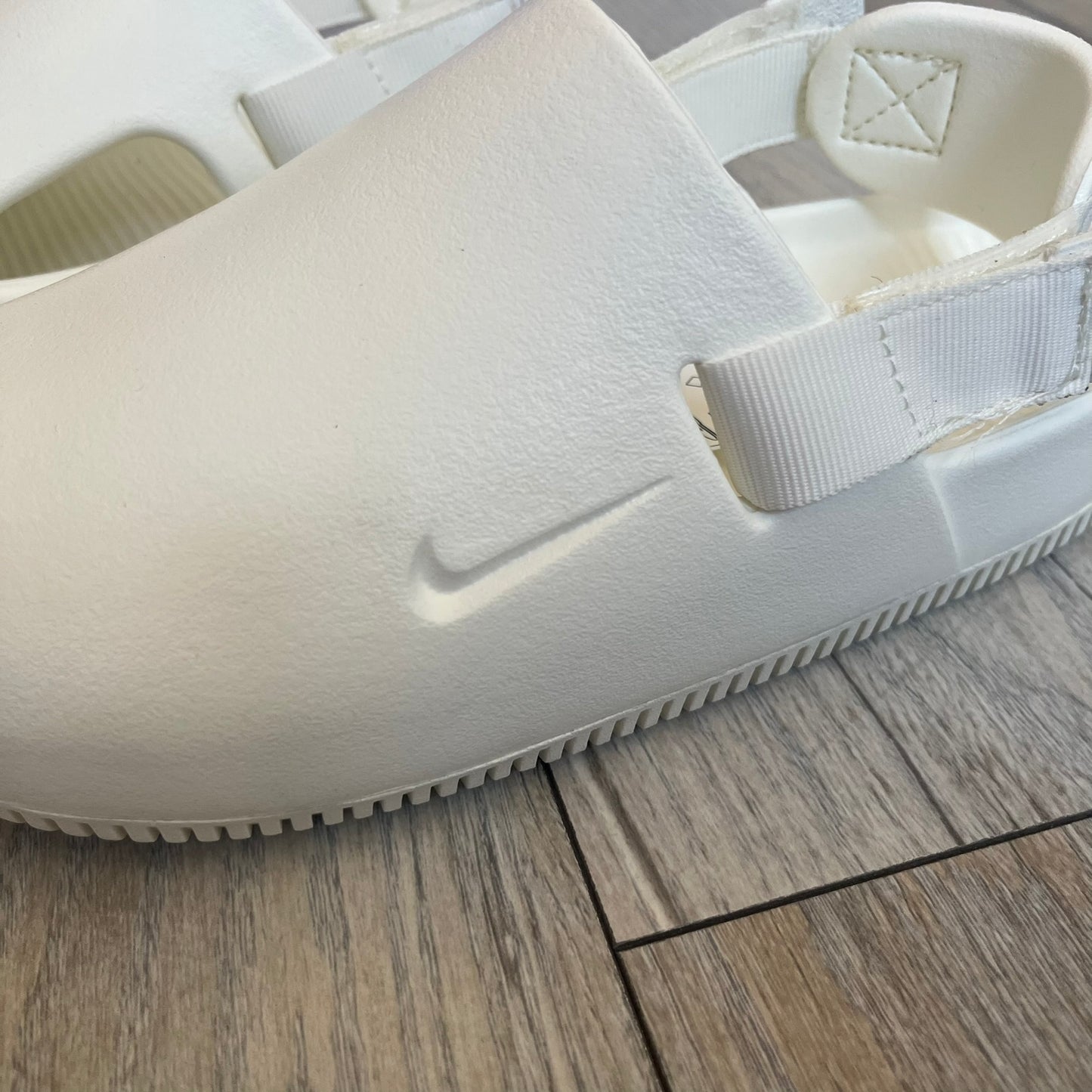 Nike Calm Mule Wmns White Sandals FB2185-100 are women’s slip-on mules finished in a Sail/White colorway, constructed from a single-piece foam upper for a seamless design. The model features water-resistant, easy-to-clean foam with a textured footbed and full-length rubber outsole for traction on wet surfaces. An adjustable and removable heel strap allows for a customizable fit, while side openings provide ventilation.