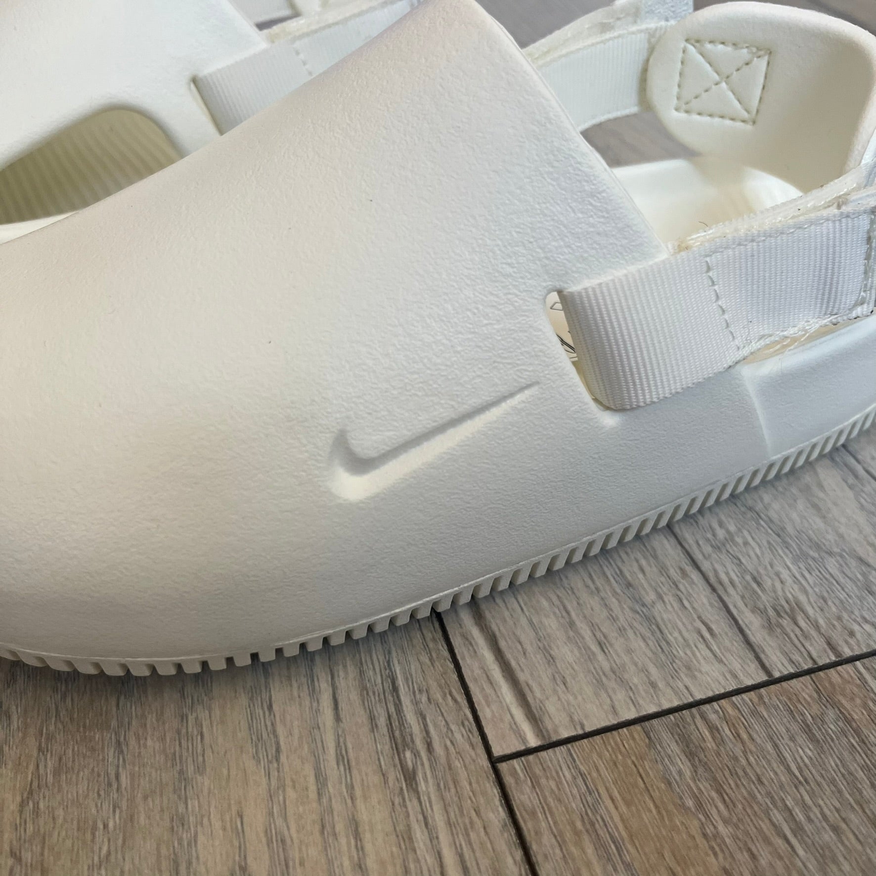 Nike Calm Mule Wmns White Sandals FB2185-100 are women’s slip-on mules finished in a Sail/White colorway, constructed from a single-piece foam upper for a seamless design. The model features water-resistant, easy-to-clean foam with a textured footbed and full-length rubber outsole for traction on wet surfaces. An adjustable and removable heel strap allows for a customizable fit, while side openings provide ventilation.