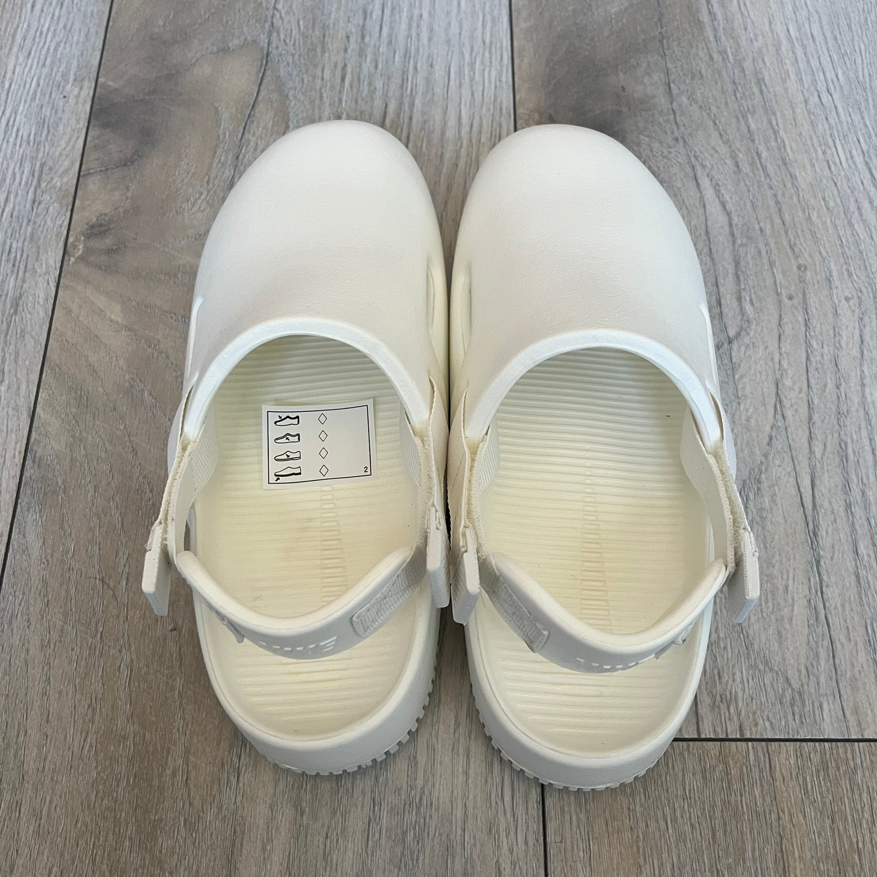 Nike Calm Mule Wmns White Sandals FB2185-100 are women’s slip-on mules finished in a Sail/White colorway, constructed from a single-piece foam upper for a seamless design. The model features water-resistant, easy-to-clean foam with a textured footbed and full-length rubber outsole for traction on wet surfaces. An adjustable and removable heel strap allows for a customizable fit, while side openings provide ventilation.