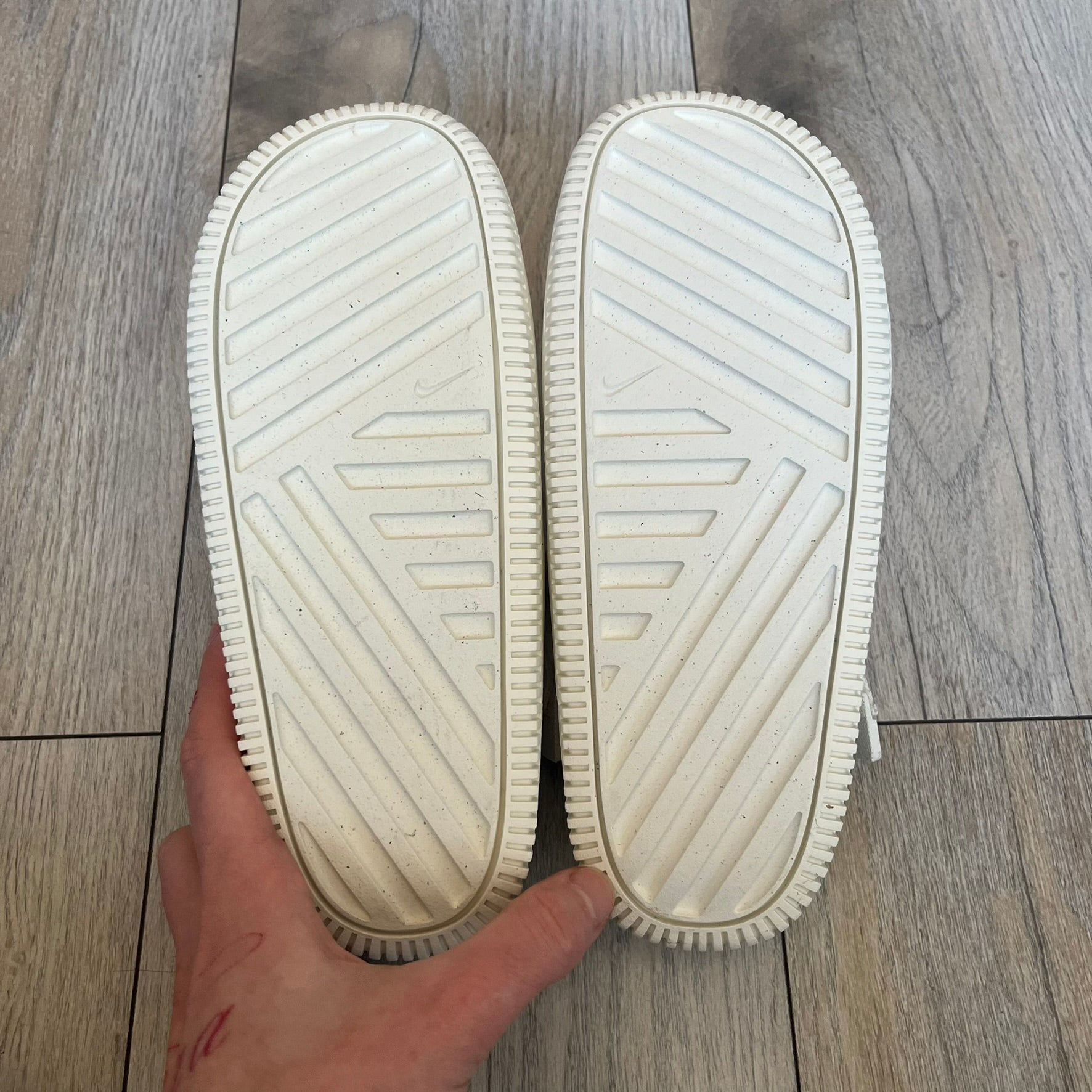 Nike Calm Mule Wmns White Sandals FB2185-100 are women’s slip-on mules finished in a Sail/White colorway, constructed from a single-piece foam upper for a seamless design. The model features water-resistant, easy-to-clean foam with a textured footbed and full-length rubber outsole for traction on wet surfaces. An adjustable and removable heel strap allows for a customizable fit, while side openings provide ventilation.