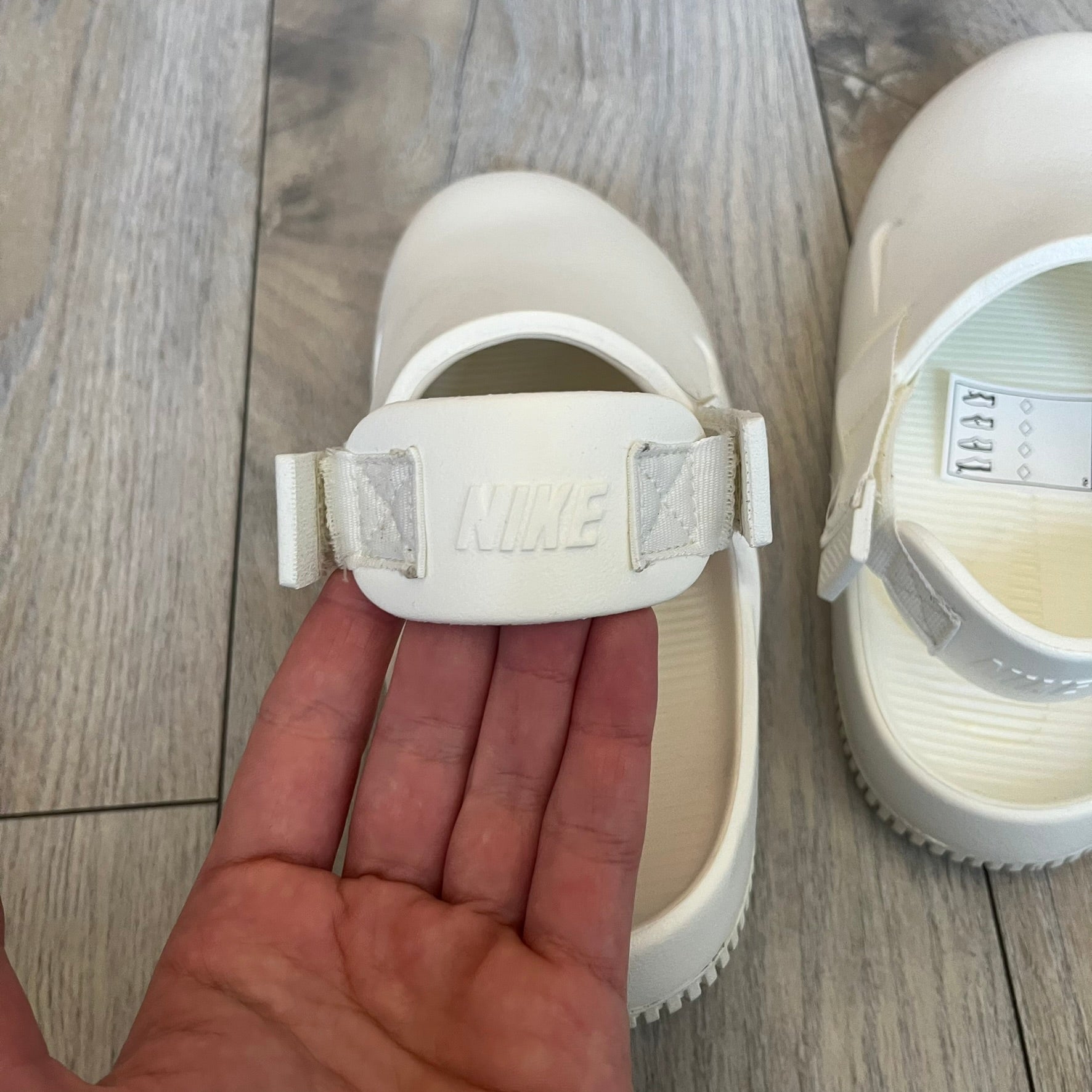 Nike Calm Mule Wmns White Sandals FB2185-100 are women’s slip-on mules finished in a Sail/White colorway, constructed from a single-piece foam upper for a seamless design. The model features water-resistant, easy-to-clean foam with a textured footbed and full-length rubber outsole for traction on wet surfaces. An adjustable and removable heel strap allows for a customizable fit, while side openings provide ventilation.