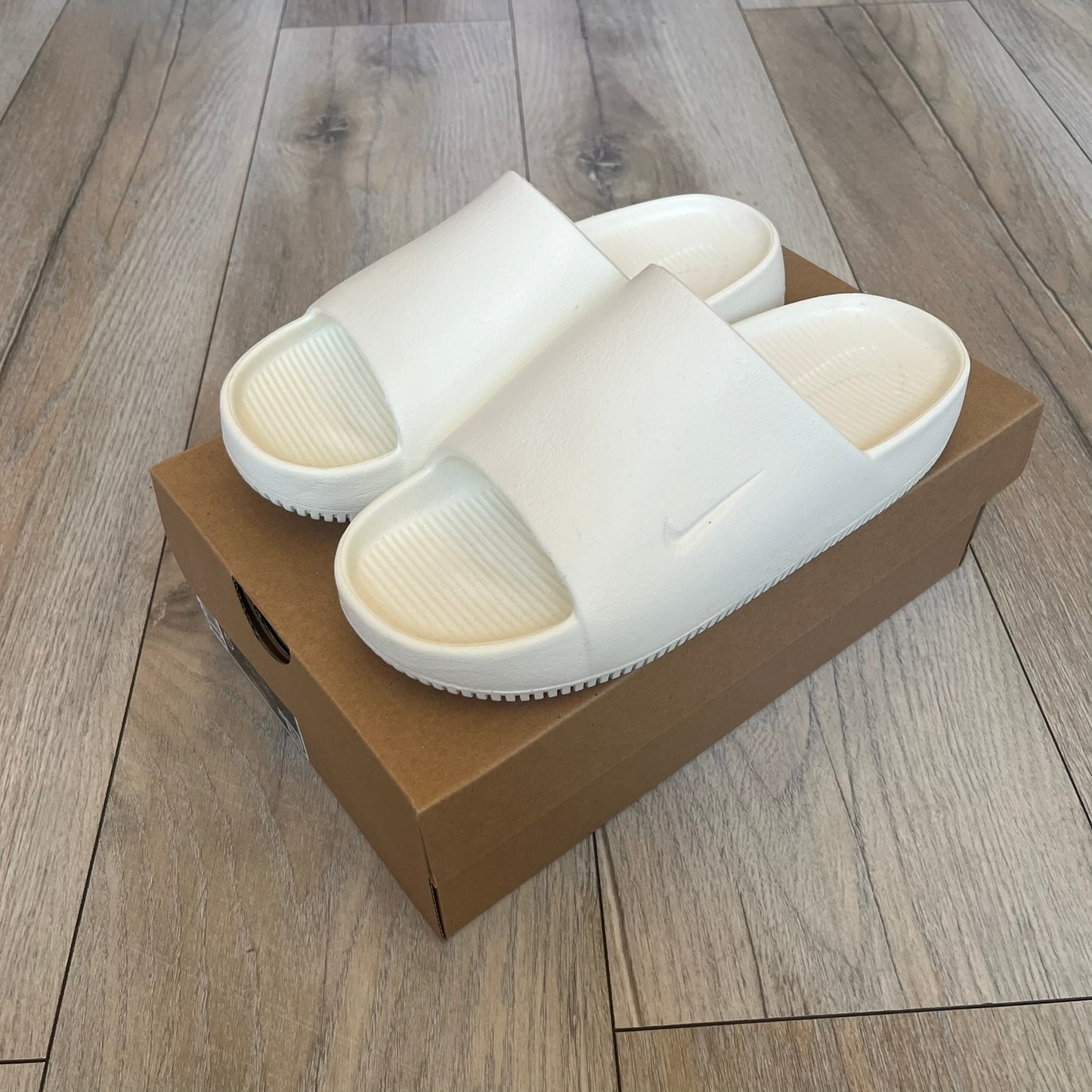 Nike Calm Wmns “Sail” Slide Sandals are women’s slip-on slides released in 2023, featuring a monochromatic Sail/White colorway and a one-piece foam construction. The design includes a contoured footbed with textured detailing for grip, a waterproof outer shell, and a midfoot strap with a debossed Nike Swoosh logo. A full rubber outsole provides durable traction, making this model suitable for everyday wear and wet conditions.