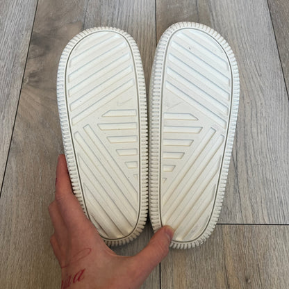 Nike Calm Wmns “Sail” Slide Sandals are women’s slip-on slides released in 2023, featuring a monochromatic Sail/White colorway and a one-piece foam construction. The design includes a contoured footbed with textured detailing for grip, a waterproof outer shell, and a midfoot strap with a debossed Nike Swoosh logo. A full rubber outsole provides durable traction, making this model suitable for everyday wear and wet conditions.