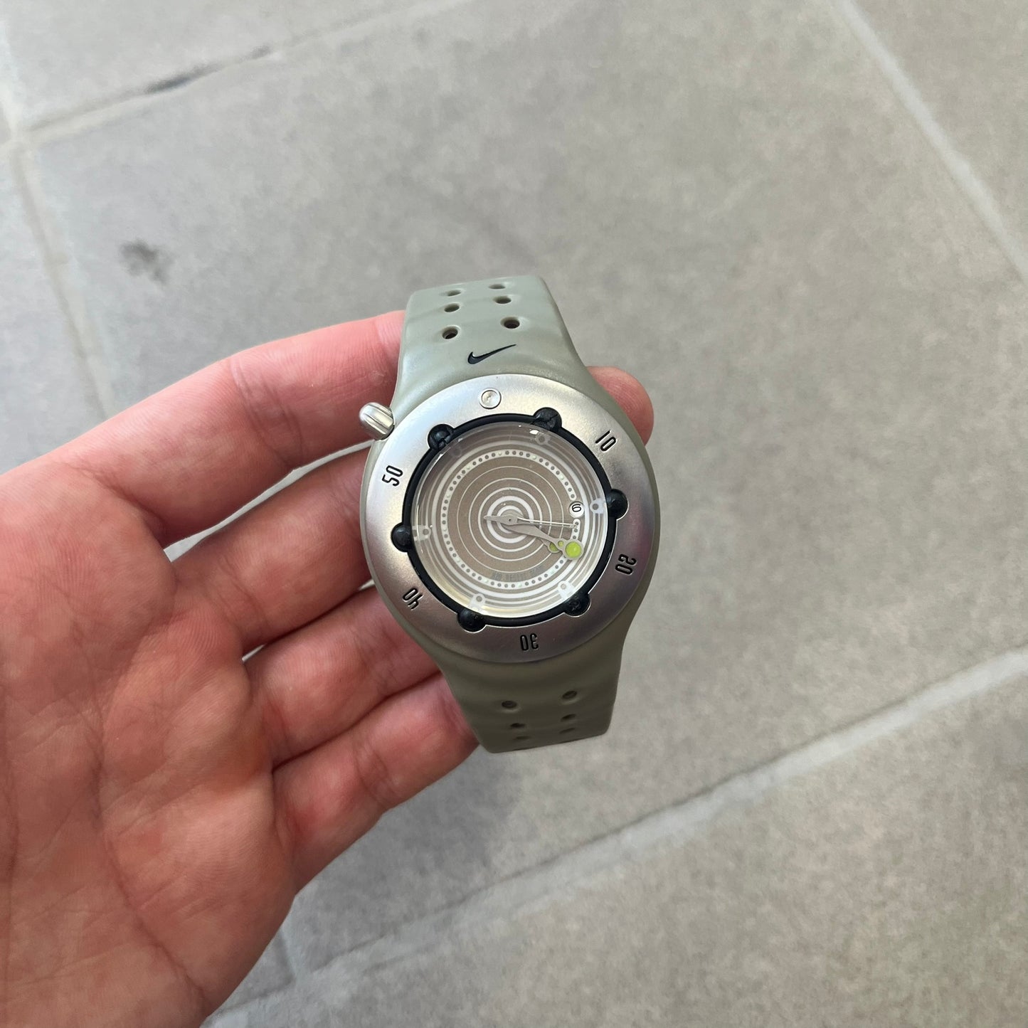 Nike Cayman WW0006 Dive Analog Watch features a grey polyurethane/rubber strap, silver rotating dive bezel, and a grey and white analog dial. It has a Japanese quartz movement, date indicator, luminous hands and hour markers, and 200-meter water resistance.
