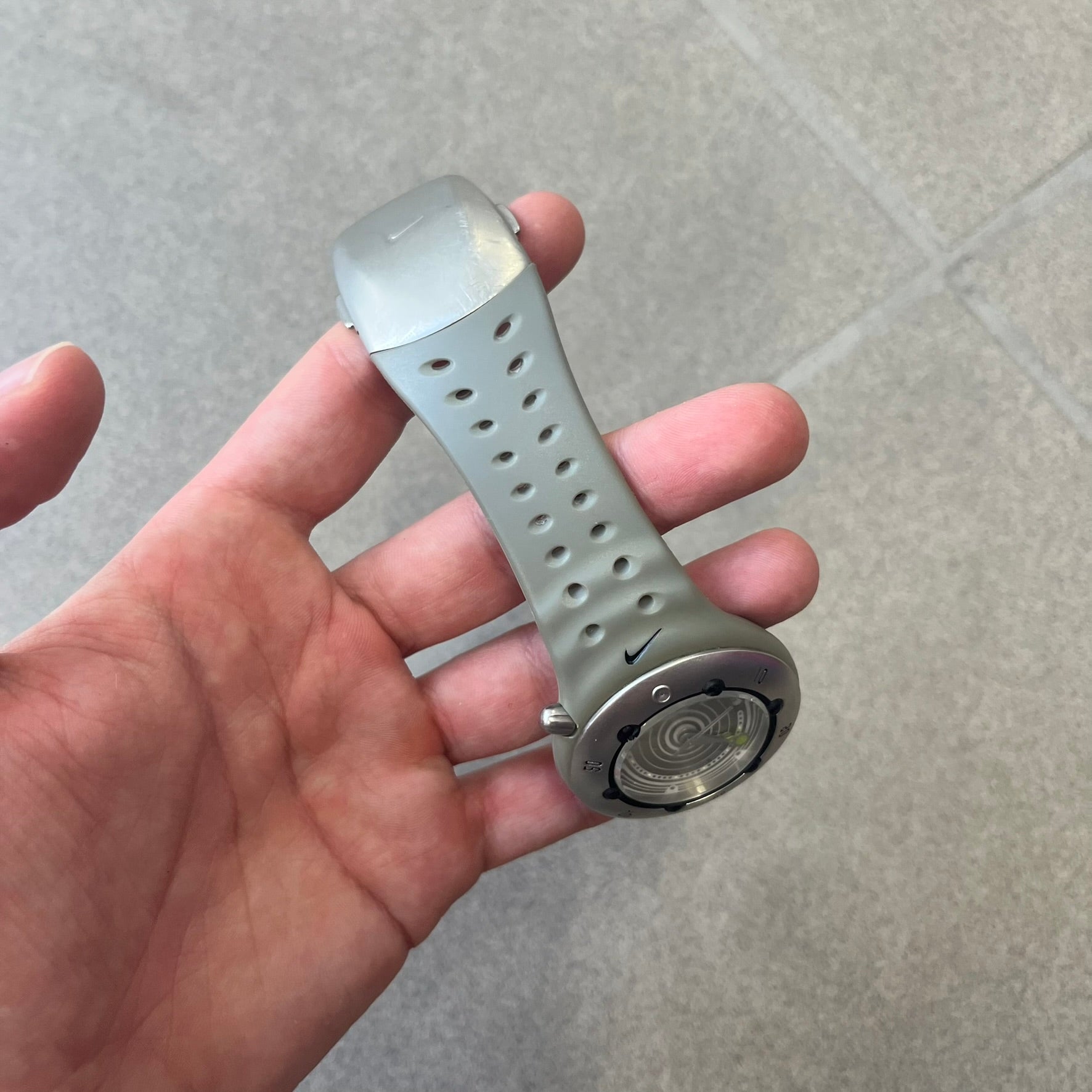 Nike Cayman WW0006 Dive Analog Watch features a grey polyurethane/rubber strap, silver rotating dive bezel, and a grey and white analog dial. It has a Japanese quartz movement, date indicator, luminous hands and hour markers, and 200-meter water resistance.
