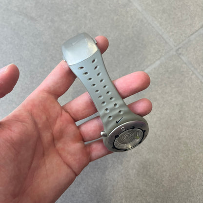 Nike Cayman WW0006 Dive Analog Watch features a grey polyurethane/rubber strap, silver rotating dive bezel, and a grey and white analog dial. It has a Japanese quartz movement, date indicator, luminous hands and hour markers, and 200-meter water resistance.
