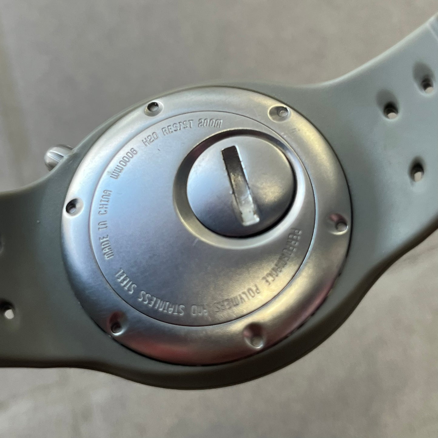 Nike Cayman WW0006 Dive Analog Watch features a grey polyurethane/rubber strap, silver rotating dive bezel, and a grey and white analog dial. It has a Japanese quartz movement, date indicator, luminous hands and hour markers, and 200-meter water resistance.
