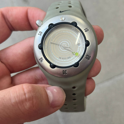 Nike Cayman WW0006 Dive Analog Watch features a grey polyurethane/rubber strap, silver rotating dive bezel, and a grey and white analog dial. It has a Japanese quartz movement, date indicator, luminous hands and hour markers, and 200-meter water resistance.
