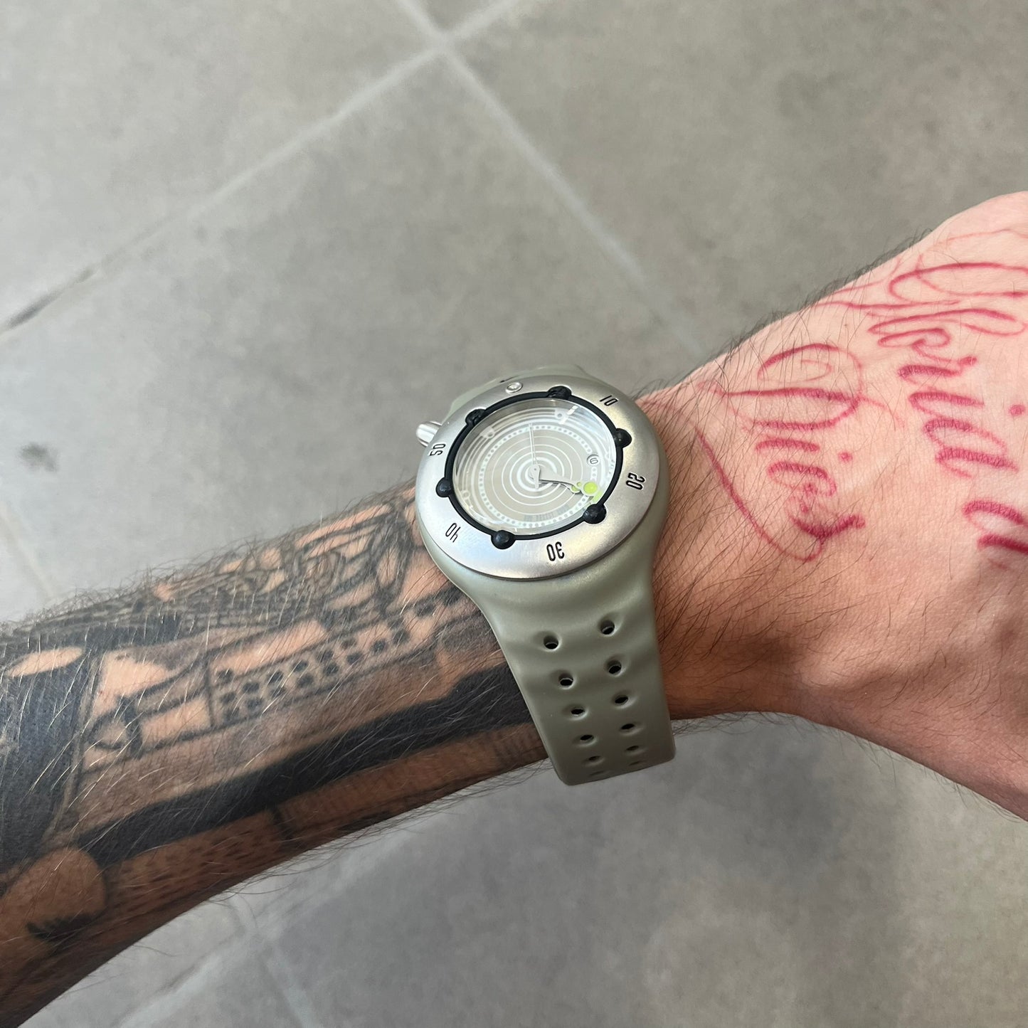 Nike Cayman WW0006 Dive Analog Watch features a grey polyurethane/rubber strap, silver rotating dive bezel, and a grey and white analog dial. It has a Japanese quartz movement, date indicator, luminous hands and hour markers, and 200-meter water resistance.
