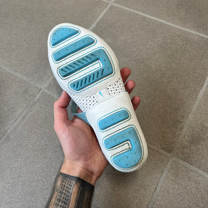 Nike City Knife 3 Barrette 2004 White Flats is a rare, packable hybrid ballet flat and athletic shoe designed by Michael DiTullo, blending a low-profile ballet-flat silhouette with technical mesh and ventilation. The white upper features perforated detailing, a small Nike Swoosh, and blue accents on the rubber top lines, interior, and sole.