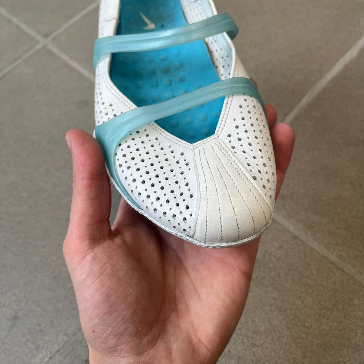Nike City Knife 3 Barrette 2004 White Flats is a rare, packable hybrid ballet flat and athletic shoe designed by Michael DiTullo, blending a low-profile ballet-flat silhouette with technical mesh and ventilation. The white upper features perforated detailing, a small Nike Swoosh, and blue accents on the rubber top lines, interior, and sole.