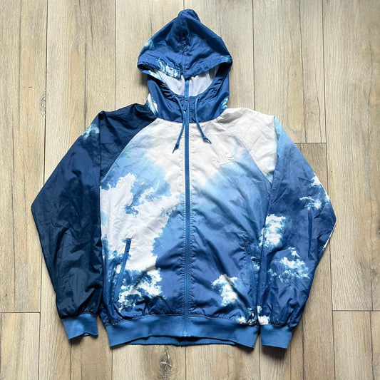 Nike Cloud Day Split Windbreaker from the 2010s in full blue with a photorealistic all-over cloud print. Features dual zippers on the front and back, allowing the jacket to split in half and merge with other compatible pieces. Made from 100% nylon.
