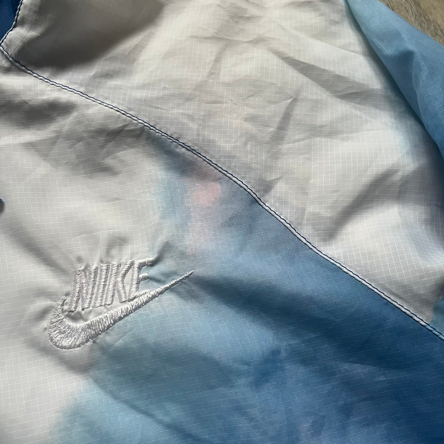 Nike Cloud Day Split Windbreaker from the 2010s in full blue with a photorealistic all-over cloud print. Features dual zippers on the front and back, allowing the jacket to split in half and merge with other compatible pieces. Made from 100% nylon.