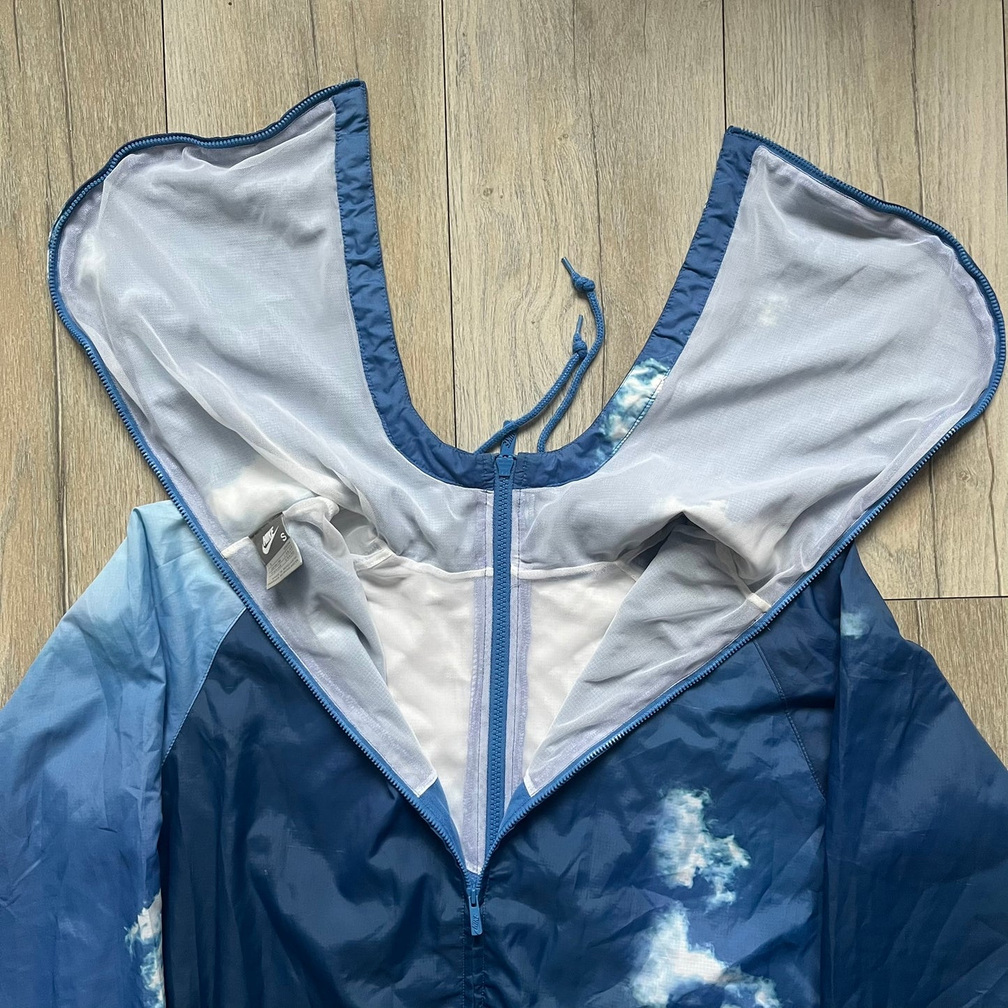 Nike Cloud Day Split Windbreaker from the 2010s in full blue with a photorealistic all-over cloud print. Features dual zippers on the front and back, allowing the jacket to split in half and merge with other compatible pieces. Made from 100% nylon.