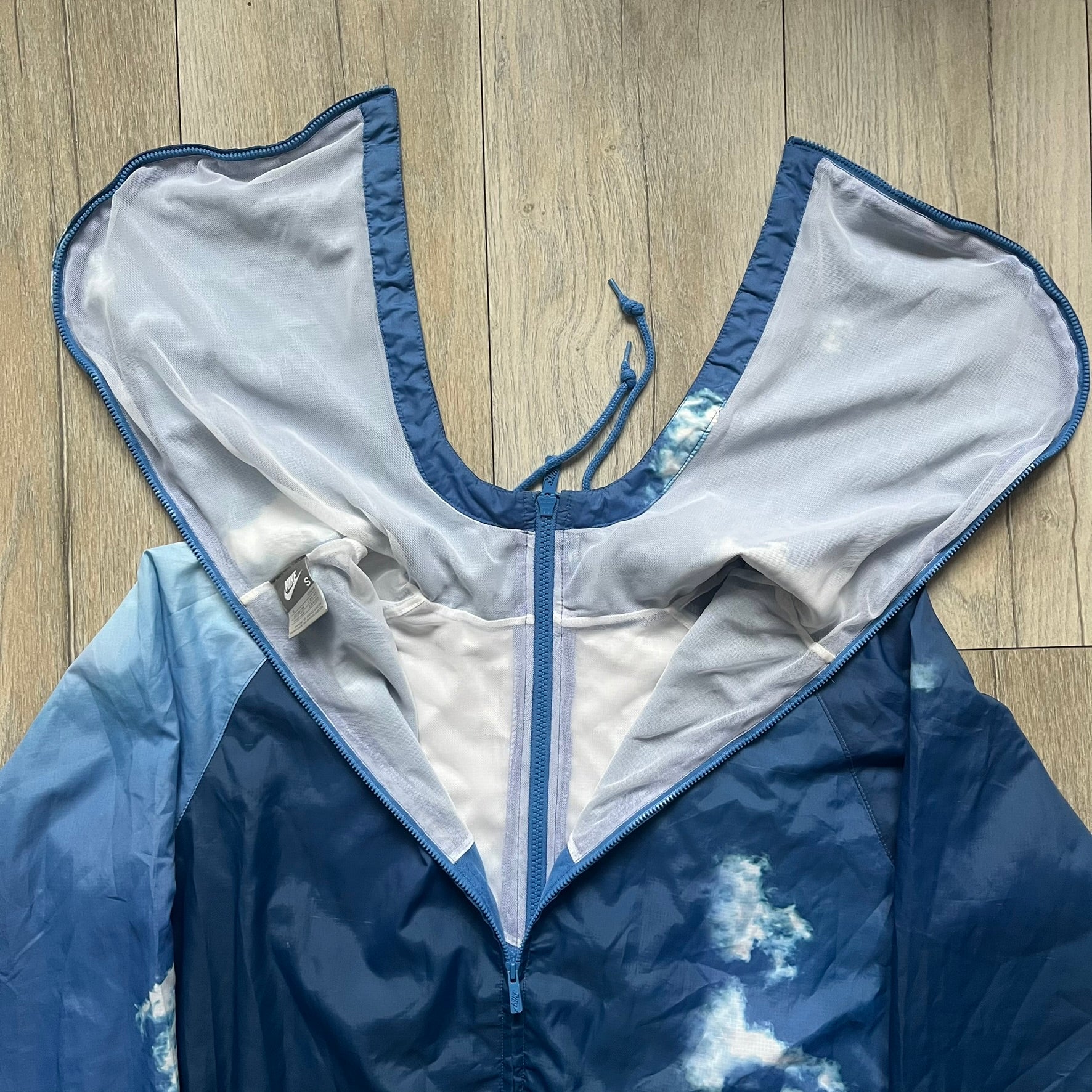 Nike Cloud Day Split Windbreaker from the 2010s in full blue with a photorealistic all-over cloud print. Features dual zippers on the front and back, allowing the jacket to split in half and merge with other compatible pieces. Made from 100% nylon.