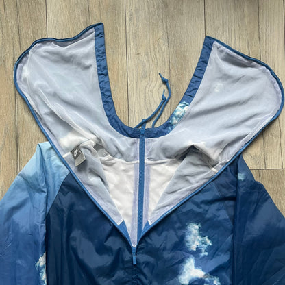 Nike Cloud Day Split Windbreaker from the 2010s in full blue with a photorealistic all-over cloud print. Features dual zippers on the front and back, allowing the jacket to split in half and merge with other compatible pieces. Made from 100% nylon.