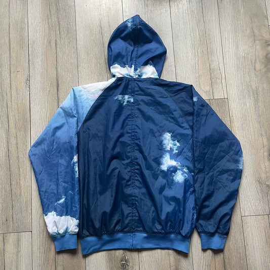 Nike Cloud Day Split Windbreaker from the 2010s in full blue with a photorealistic all-over cloud print. Features dual zippers on the front and back, allowing the jacket to split in half and merge with other compatible pieces. Made from 100% nylon.