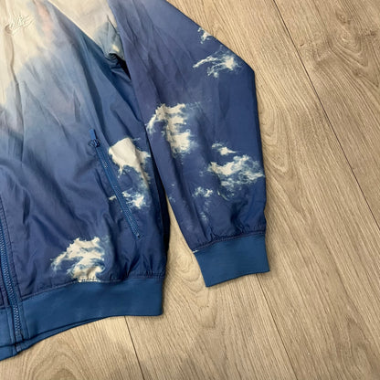 Nike Cloud Day Split Windbreaker from the 2010s in full blue with a photorealistic all-over cloud print. Features dual zippers on the front and back, allowing the jacket to split in half and merge with other compatible pieces. Made from 100% nylon.