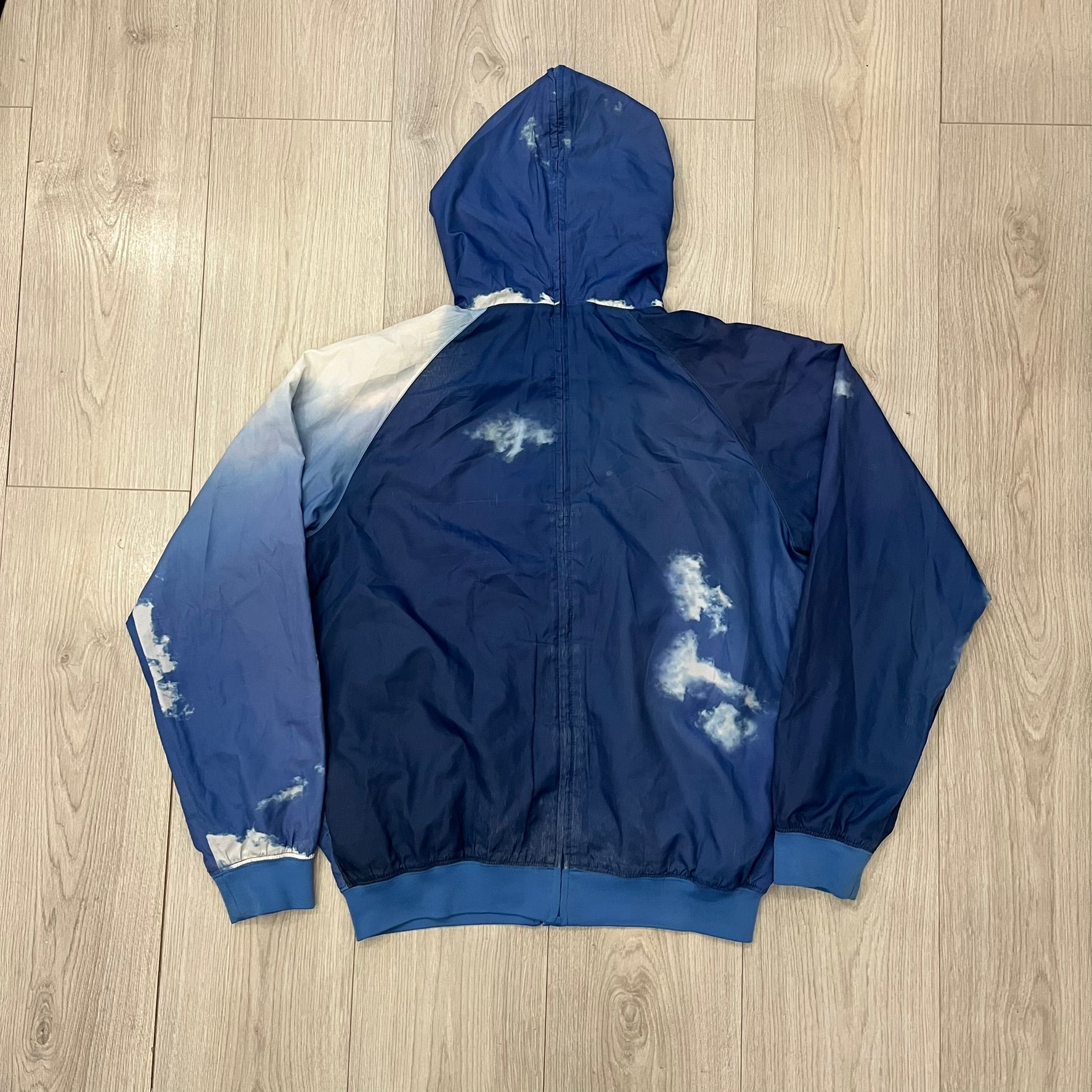 Nike Cloud Day Split Windbreaker from the 2010s in full blue with a photorealistic all-over cloud print. Features dual zippers on the front and back, allowing the jacket to split in half and merge with other compatible pieces. Made from 100% nylon.