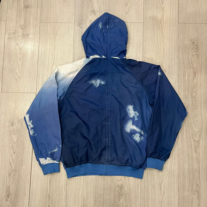 Nike Cloud Day Split Windbreaker from the 2010s in full blue with a photorealistic all-over cloud print. Features dual zippers on the front and back, allowing the jacket to split in half and merge with other compatible pieces. Made from 100% nylon.