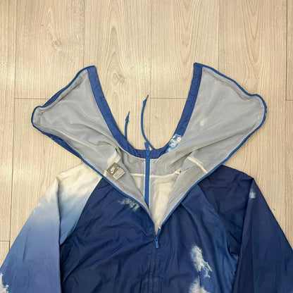 Nike Cloud Day Split Windbreaker from the 2010s in full blue with a photorealistic all-over cloud print. Features dual zippers on the front and back, allowing the jacket to split in half and merge with other compatible pieces. Made from 100% nylon.