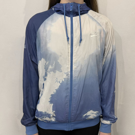 Nike Cloud Day Split Windbreaker from the 2010s in full blue with a photorealistic all-over cloud print. Features dual zippers on the front and back, allowing the jacket to split in half and merge with other compatible pieces. Made from 100% nylon.