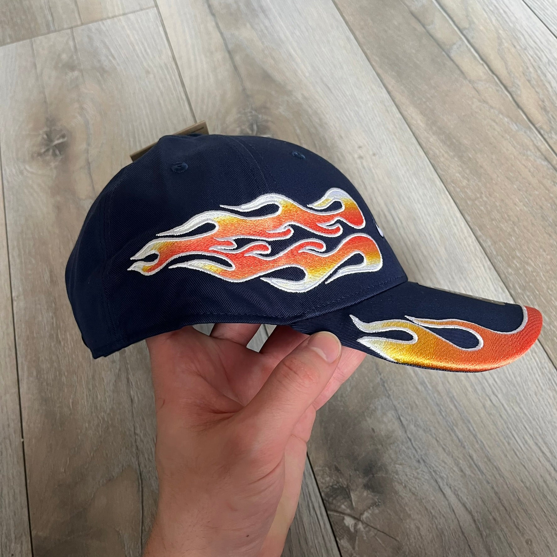 Nike Club Semi-Structured OG Midnight Navy Flame Cap is a navy baseball cap featuring a white Nike Swoosh centered on the front panel. Embroidered flame graphics in orange, yellow, and red extend across the front of the visor and side panels. A small white Nike Swoosh is placed at the back. The design is identified by code IH9258-410.