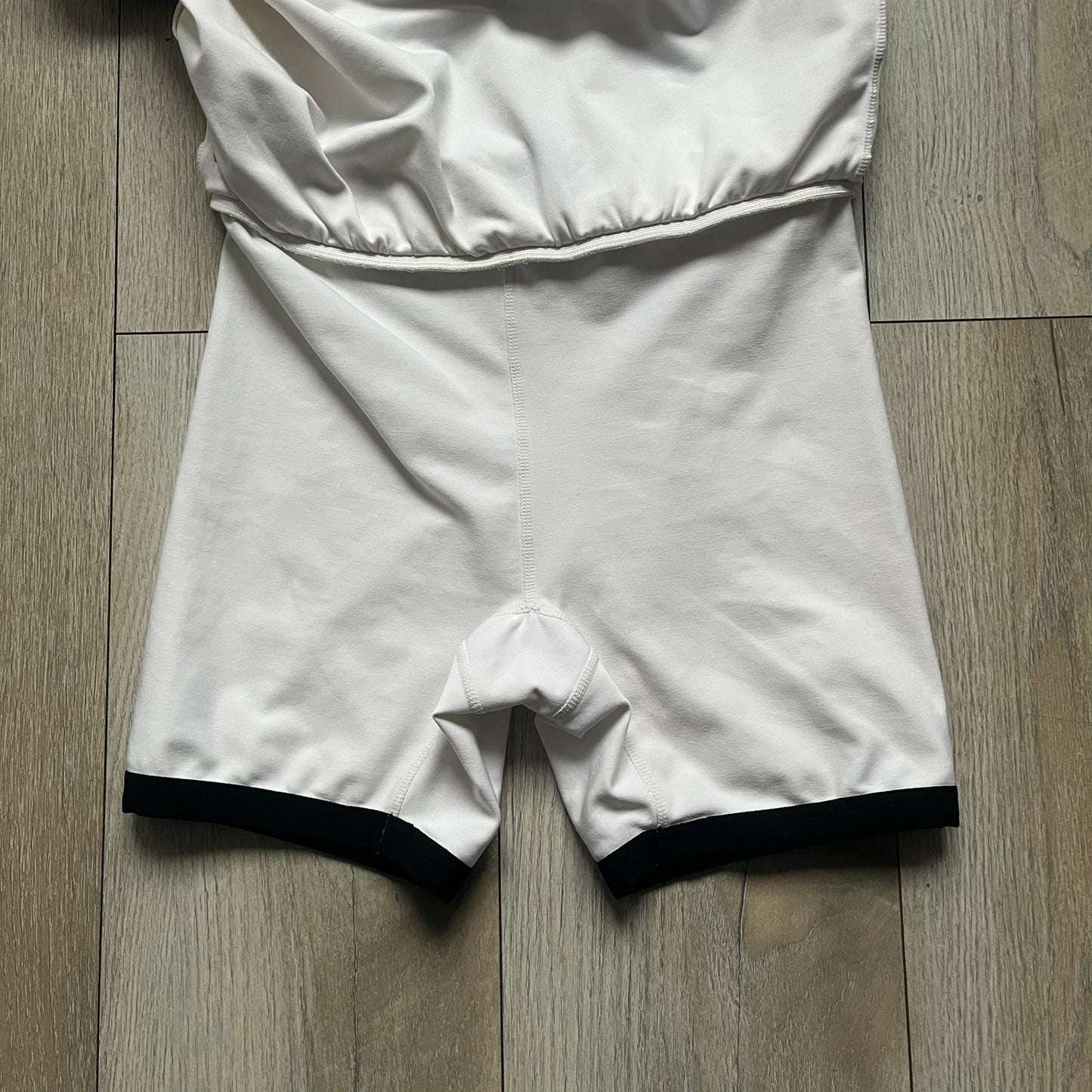 Nike Court Black Trim 90’s Tennis Skirt is a white women’s tennis skort with built-in inner shorts. It features a small Nike Court logo at the lower right hem and black trim detailing along the skirt hem and the bottom of the inner shorts legs.