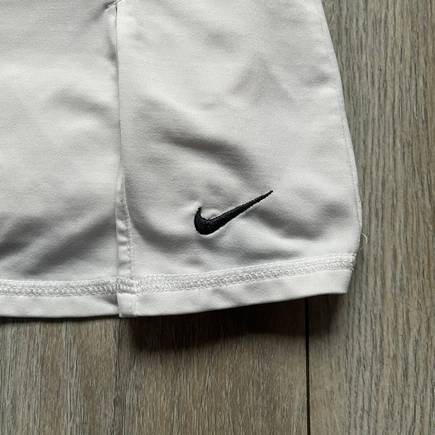 Nike Court Flex Pure Tennis Skirt is a kids’ tennis skort with integrated inner shorts for coverage and support. The skirt is white with a black Nike Swoosh at the lower hem and a Nike Court logo on the opposite side. The front features cut-out sections on both sides for added comfort and mobility.