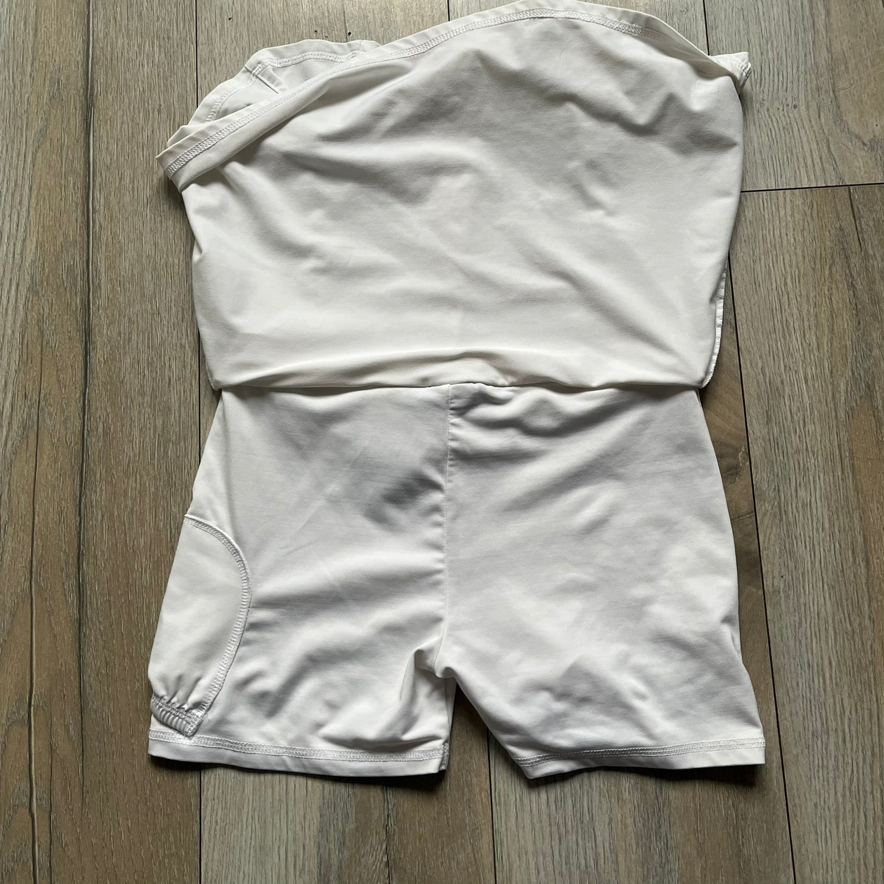 Nike Court Flex Pure Tennis Skirt is a kids’ tennis skort with integrated inner shorts for coverage and support. The skirt is white with a black Nike Swoosh at the lower hem and a Nike Court logo on the opposite side. The front features cut-out sections on both sides for added comfort and mobility.
