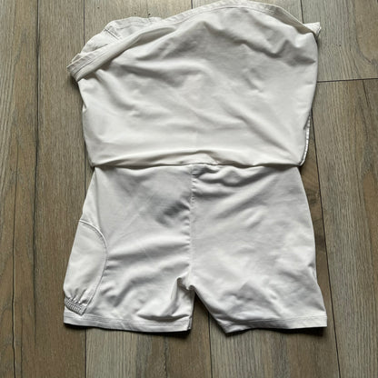Nike Court Flex Pure Tennis Skirt is a kids’ tennis skort with integrated inner shorts for coverage and support. The skirt is white with a black Nike Swoosh at the lower hem and a Nike Court logo on the opposite side. The front features cut-out sections on both sides for added comfort and mobility.