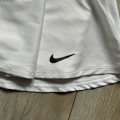Nike Court Victory Tennis Skirt is a kids’ tennis skort with built-in inner shorts for coverage. The skirt features a textured fabric with fine linear detailing, while the waistband remains smooth, and a black Nike Swoosh is placed at the lower hem. The design includes a pleated section.