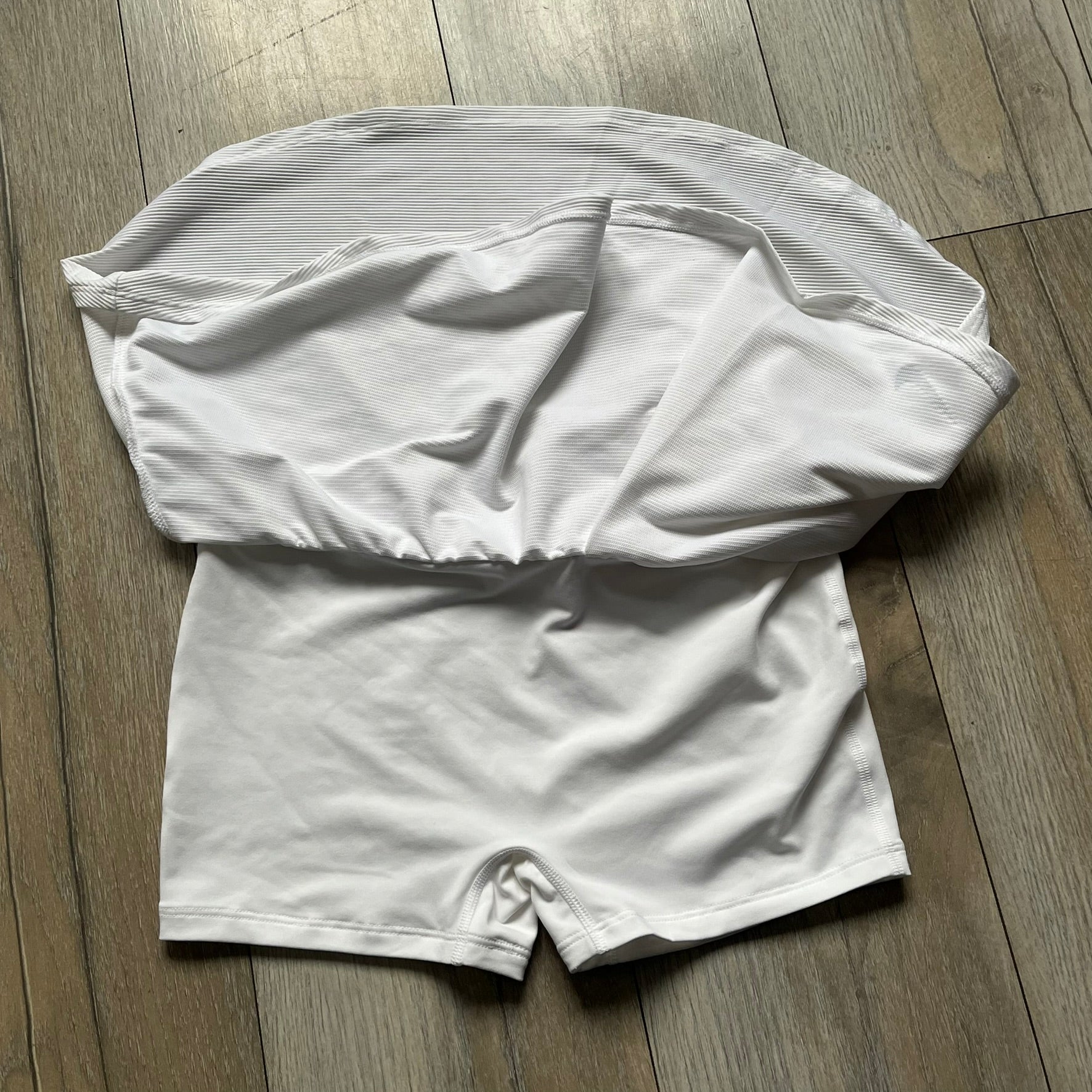 Nike Court Victory Tennis Skirt is a kids’ tennis skort with built-in inner shorts for coverage. The skirt features a textured fabric with fine linear detailing, while the waistband remains smooth, and a black Nike Swoosh is placed at the lower hem. The design includes a pleated section.