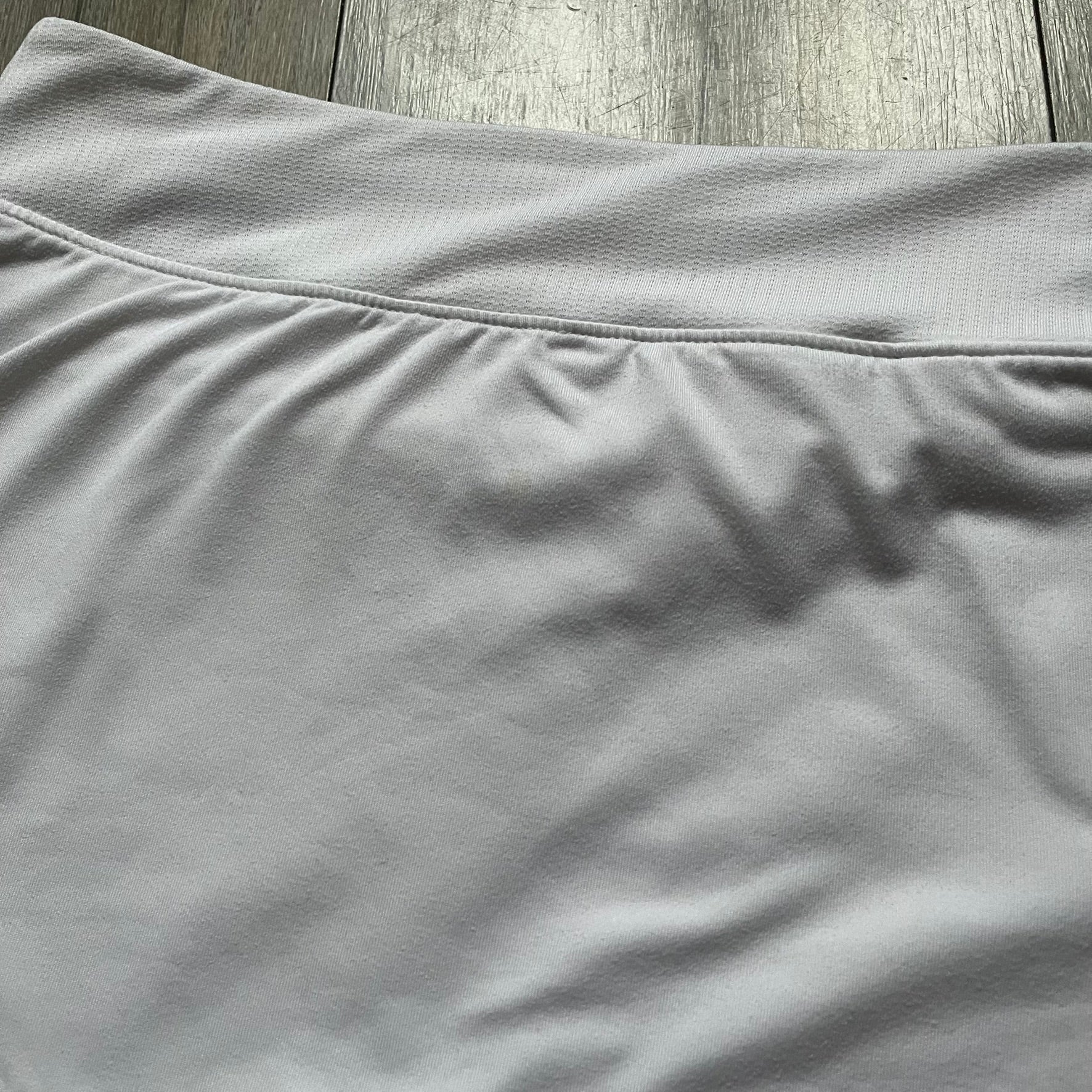 Nike Court Victory W Tennis Skirt is a women’s tennis skort with built-in inner shorts for coverage. The skirt is white with a Nike Swoosh at the lower hem and features a triangular cutout detail next to the logo for added mobility.