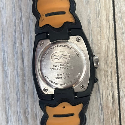 Nike Cross Training VG72-5000 Analog Watch is a 2000s model featuring a black strap, silver-tone stainless steel case, and black dial. The oval-shaped case has a flattened top with an orange Nike Swoosh positioned above the dial. It uses a three-hand analog display and includes an additional button above the crown to operate the backlight.