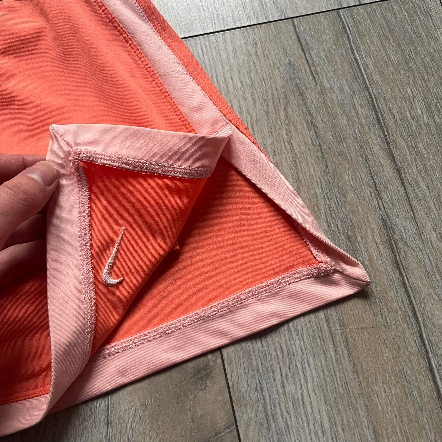 Nike Dri-FIT Orange Tennis Skirt is a women’s tennis skort with built-in shorts for coverage and support. The skirt is finished in orange with lighter side panels and embroidered Nike Swoosh at the lower hem. A small Nike Court logo on the side highlights its connection to Nike’s performance tennis line.