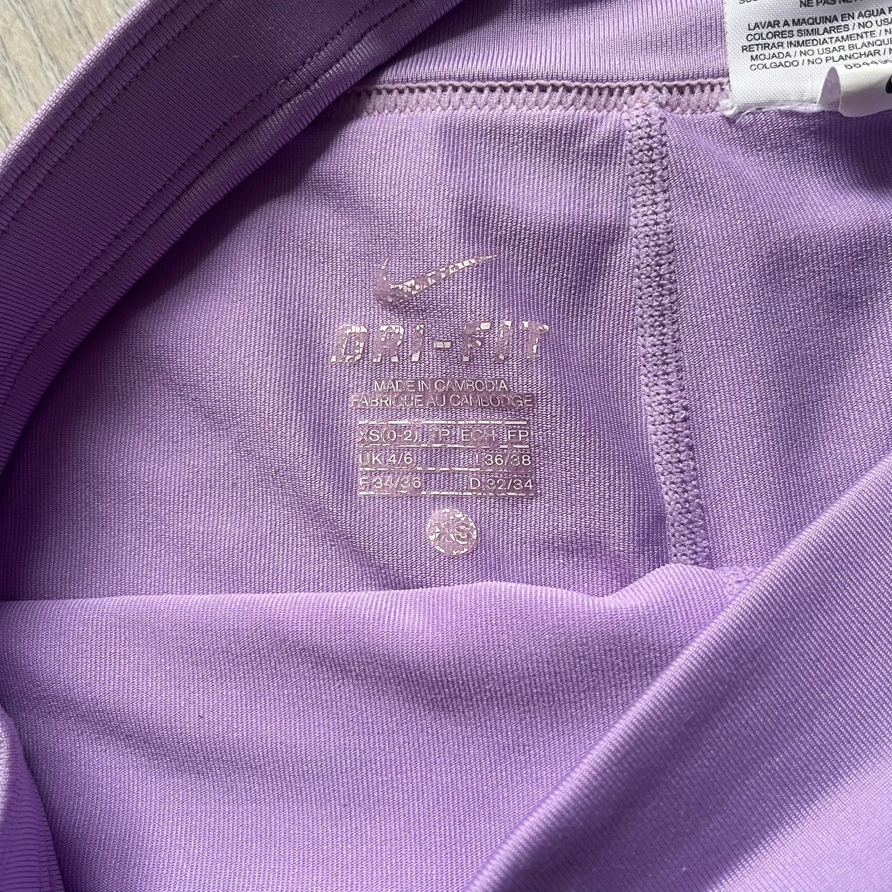 Nike Dri-FIT Striped Lavender Tennis Skirt is a women’s tennis skort with integrated inner shorts for coverage and support. The skirt features diagonal white and lavender stripes on the front and back, a small Nike Court logo on the side, and an embroidered lavender Swoosh at the lower front. The lavender waistband and side cutouts provide comfort and mobility during play.