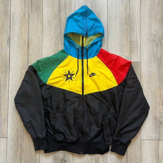 Nike Ethiopia Olympics 2008 Split Windbreaker is a performance jacket designed by Jarrett Reynolds for the Olympic collection. The jacket features a black lower section, yellow upper body, blue hood, green shoulder and red opposite shoulder. The chest is finished with an embroidered Nike logo and Ethiopia emblem. The jacket features a unique split construction that allows it to be unzipped along both sides and connected with other compatible jackets. Hidden inside, a small Ethiopia flags accent completes th